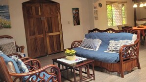 Un salón espacioso con muebles de madera, un ventilador de techo y un gran puerta de madera.