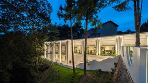 A modern building with a curved facade, large windows, and a well-maintained garden. - MisooHi Hidden Realm Hotel (Huangshan)