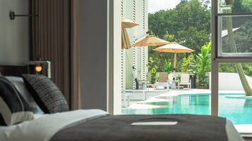 A bedroom with a view of a swimming pool and outdoor seating area.