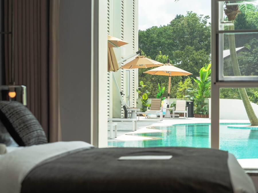 A bedroom with a view of a swimming pool and outdoor seating area.