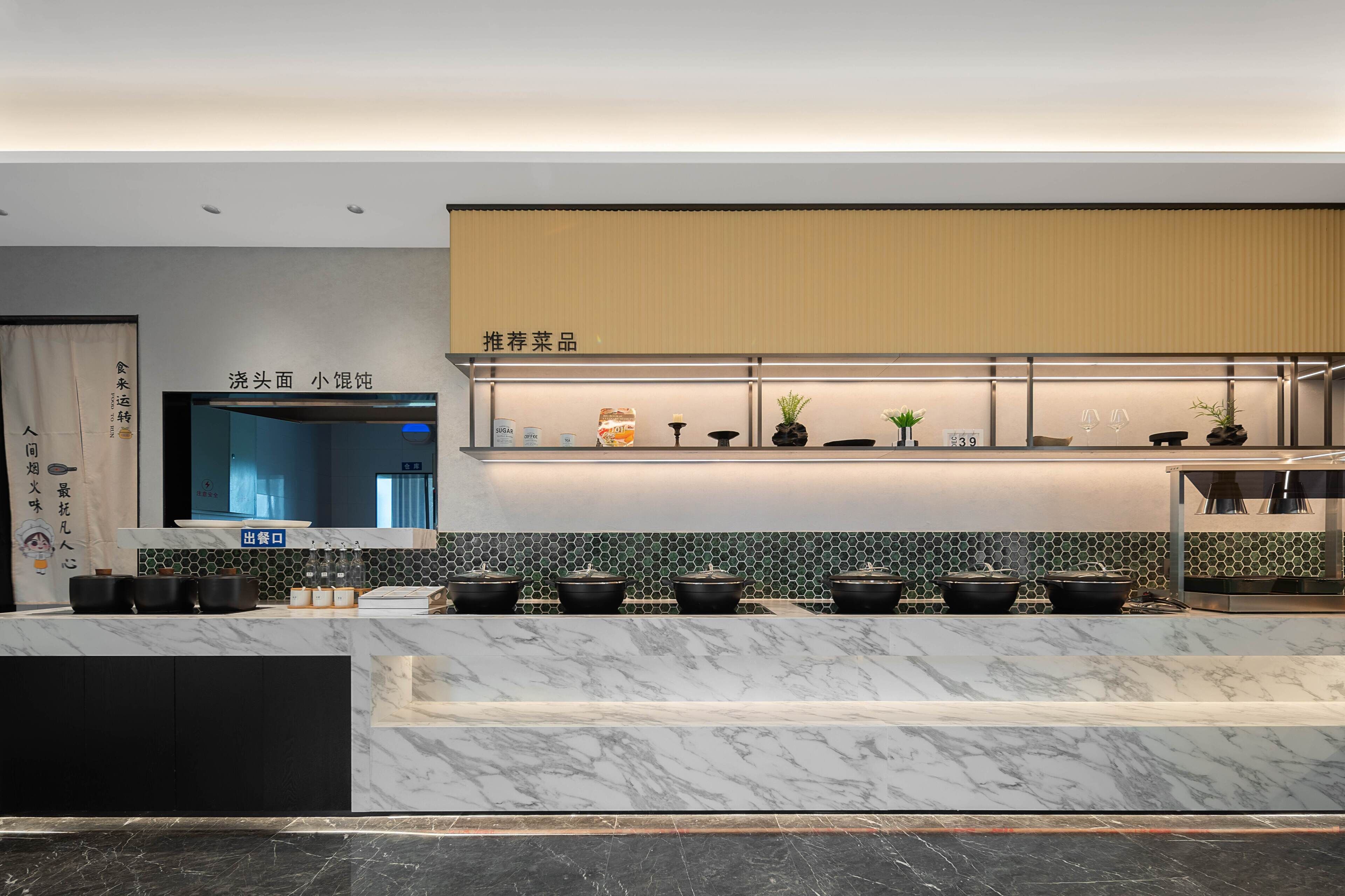 A modern kitchen with a marble countertop, a built-in stove, and a shelf with kitchenware.