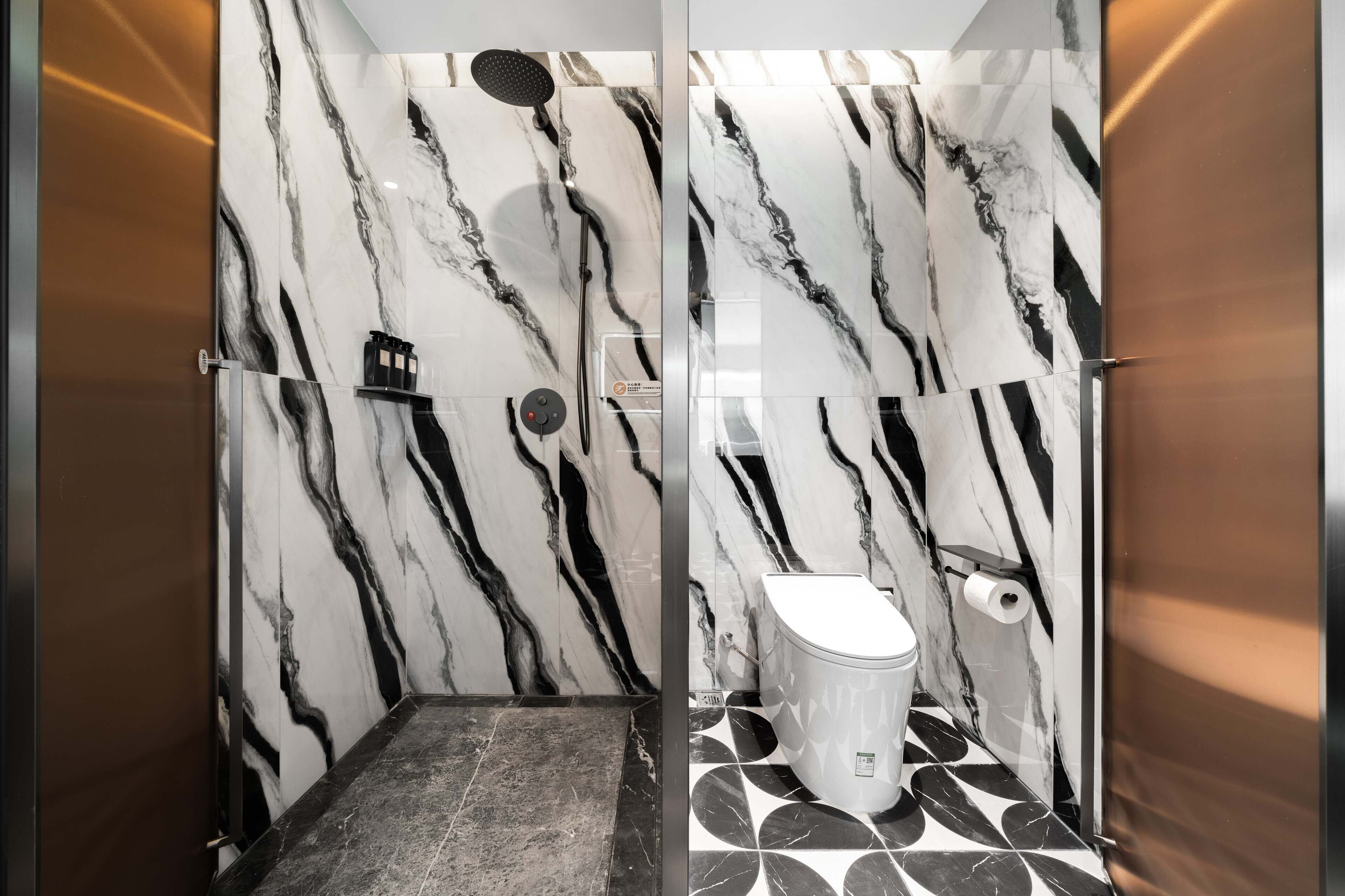 A bathroom with a marble wall, a shower, and a toilet.