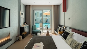 A modern hotel room with a large bed, a desk, a chair, a TV, and a view of a pool. - MisooHi Hidden Realm Hotel (Huangshan)