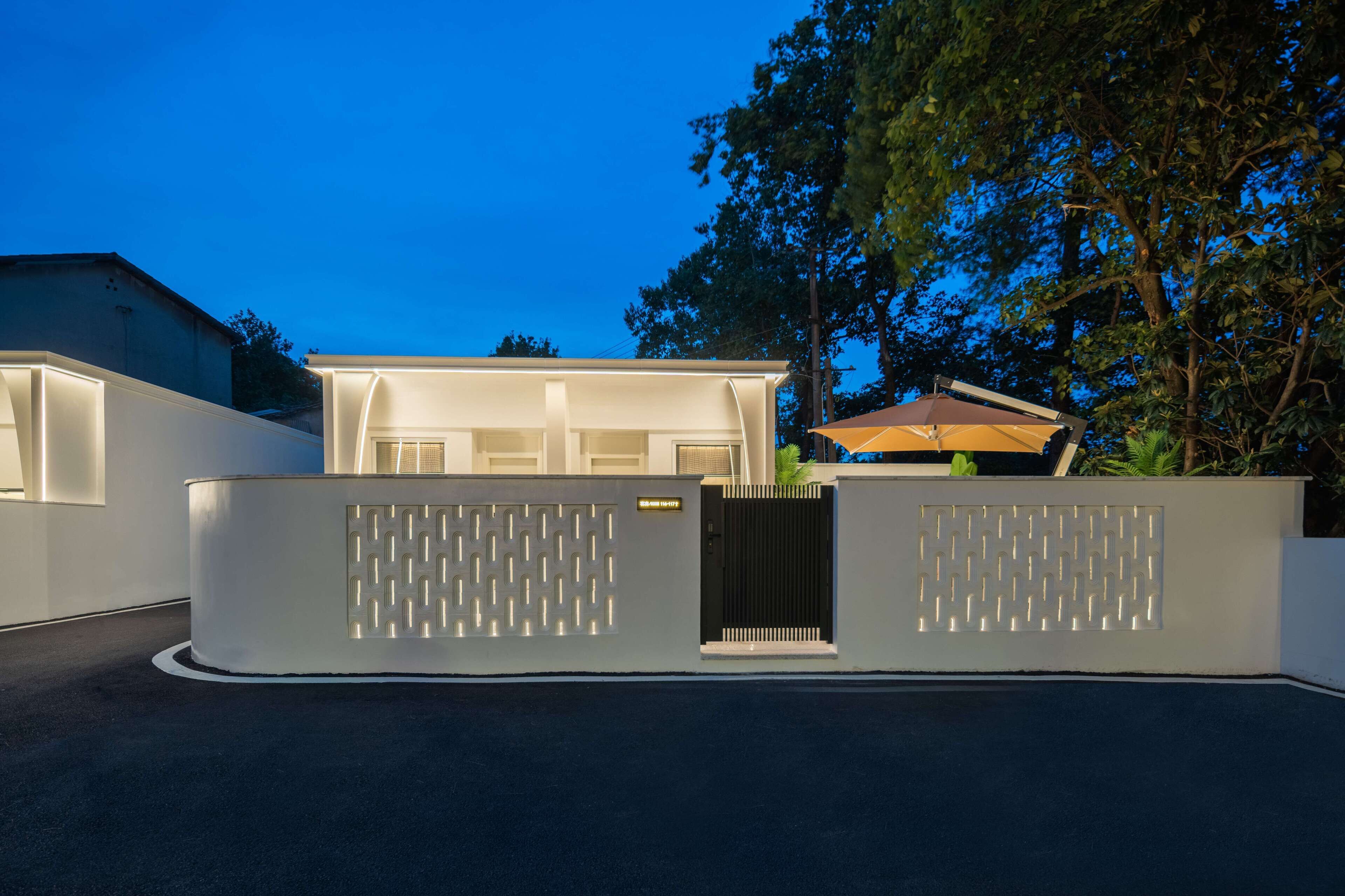 A modern house with a gated entrance, a covered patio, and a well-maintained lawn.
