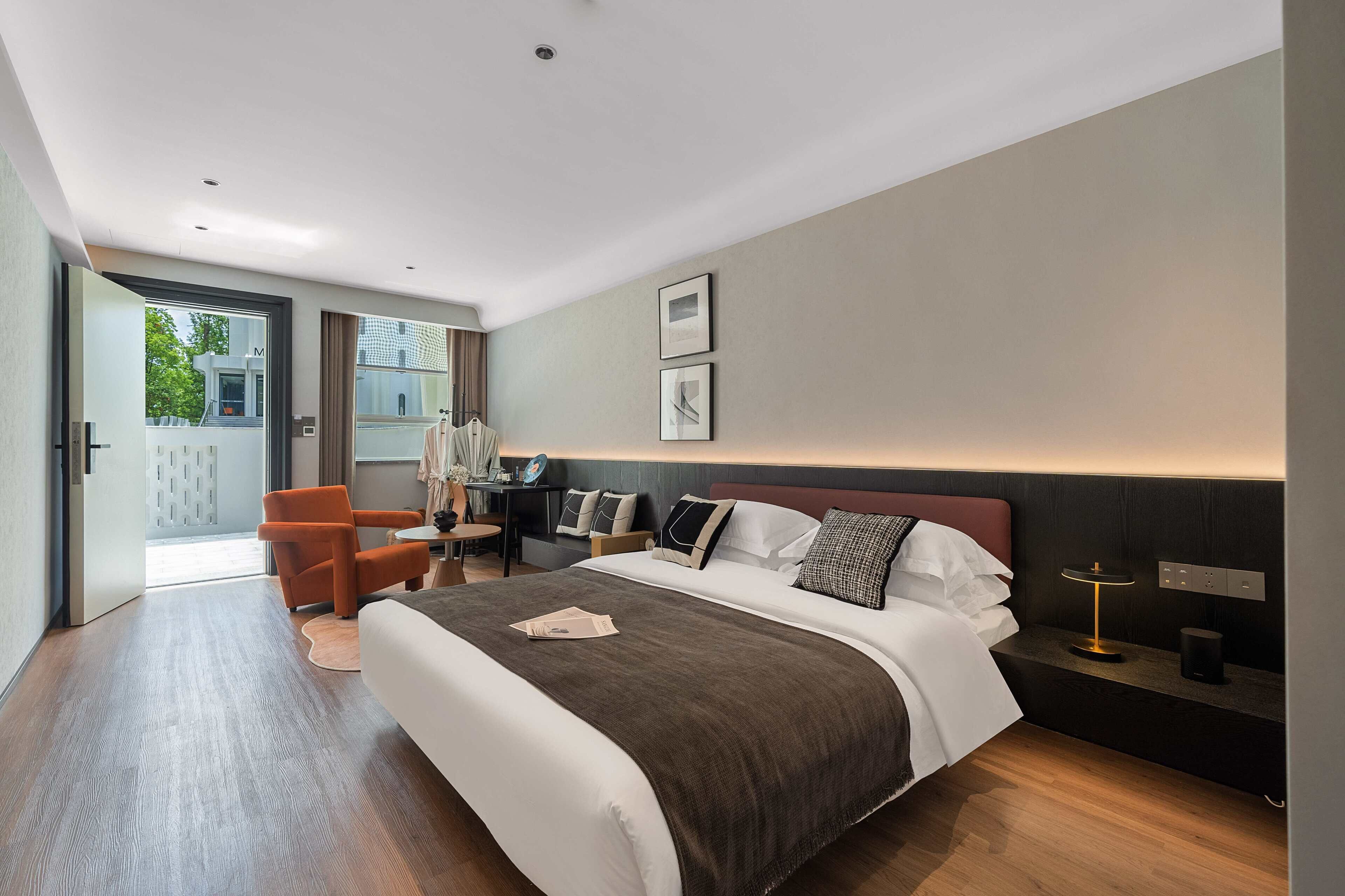 Una habitación de hotel moderna con una cama grande, un escritorio, una silla y vistas al exterior.