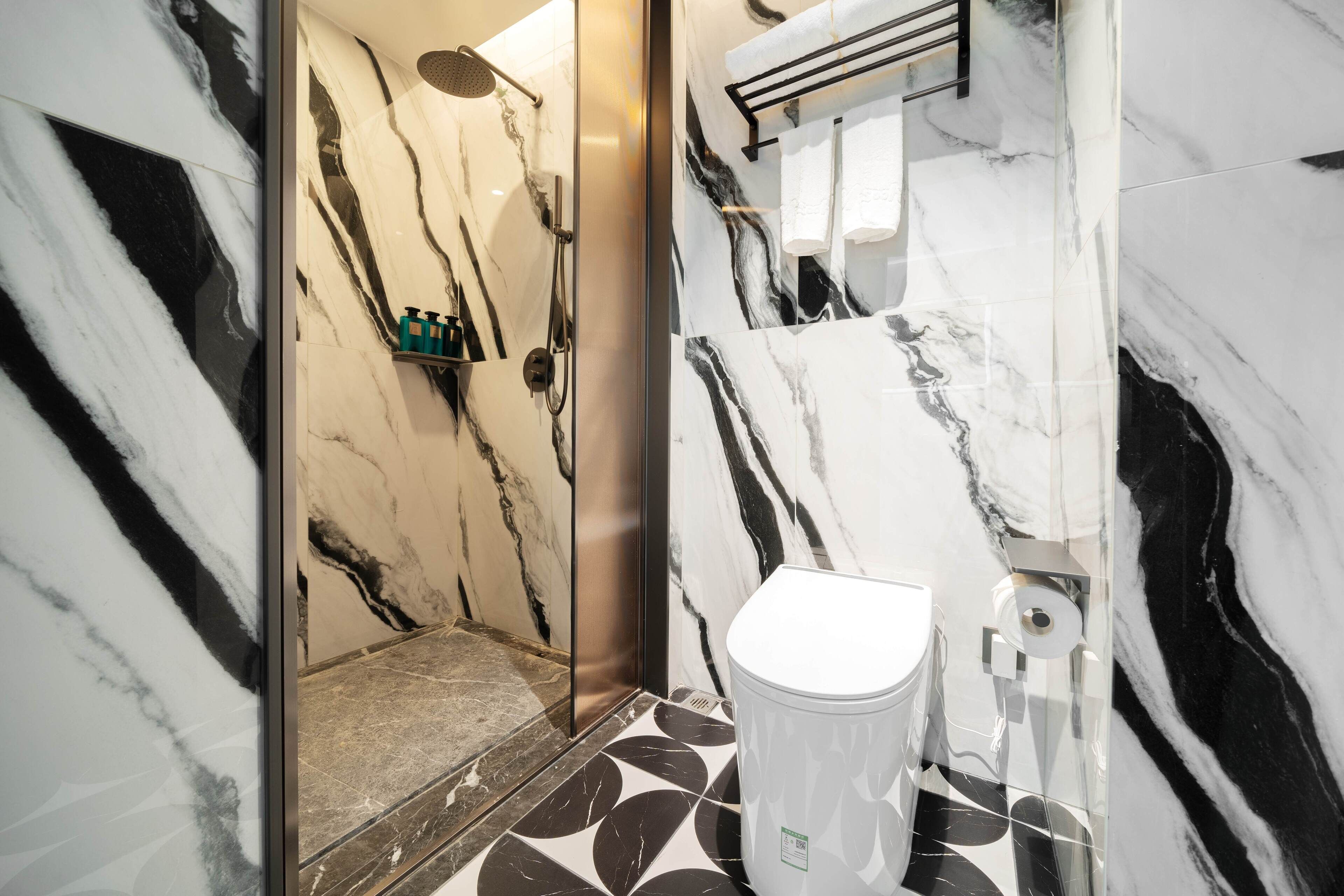 A modern bathroom with a marble floor, a white toilet, and a shower area.