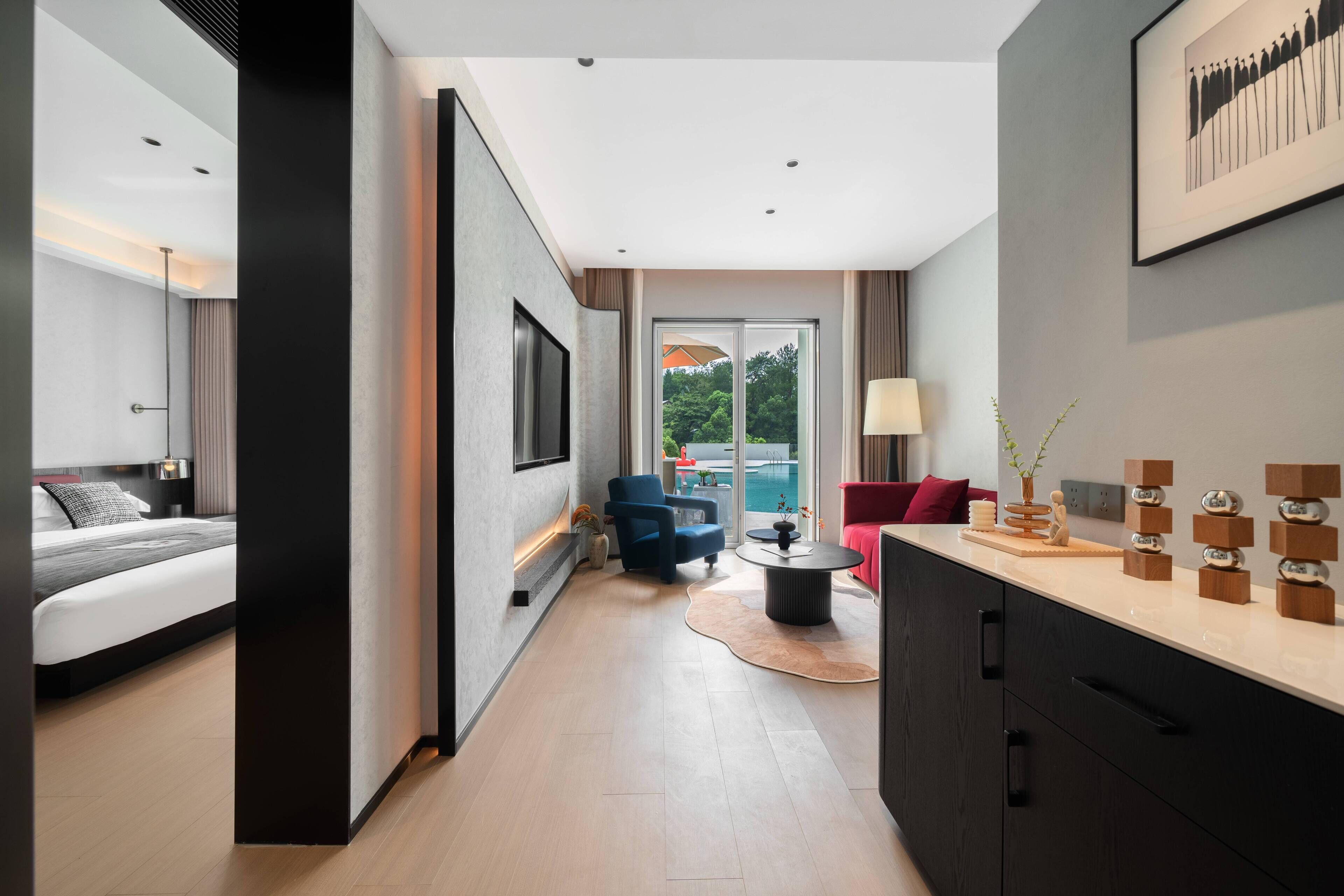 A modern hotel room with a bed, a seating area with a table, and a view of the outdoors.