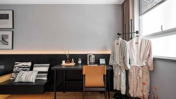 Una habitación moderna con un escritorio negro, un banco acolchado y una ventana con cortinas.