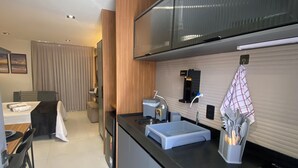 Uma cozinha moderna com bancada preta, eletrodomésticos de aço inoxidável e forno embutido.