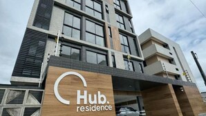 Um edifício moderno de v ários andares com uma placa grande 'Hub residence' na entrada.