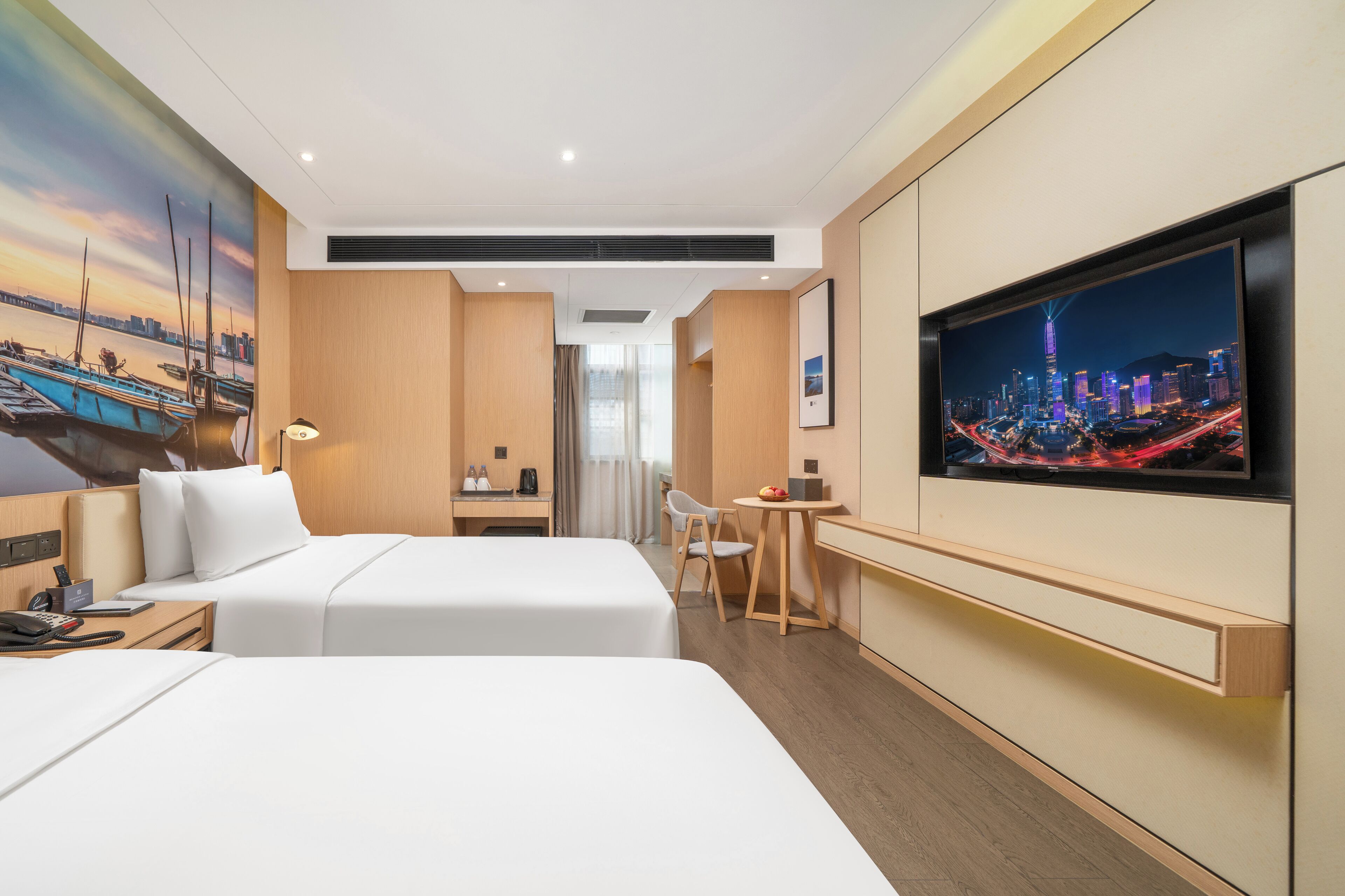 Habitación de hotel con dos camas, un escritorio, una silla, un televisor y un mural con vista a la ciudad.
