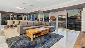 Un salon spacieux avec un grand canapé d’angle, une table basse en bois et un tapis à motifs.