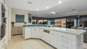 Une cuisine moderne avec des meubles blancs, un plan de travail bleu et une vue sur l’extérieur.