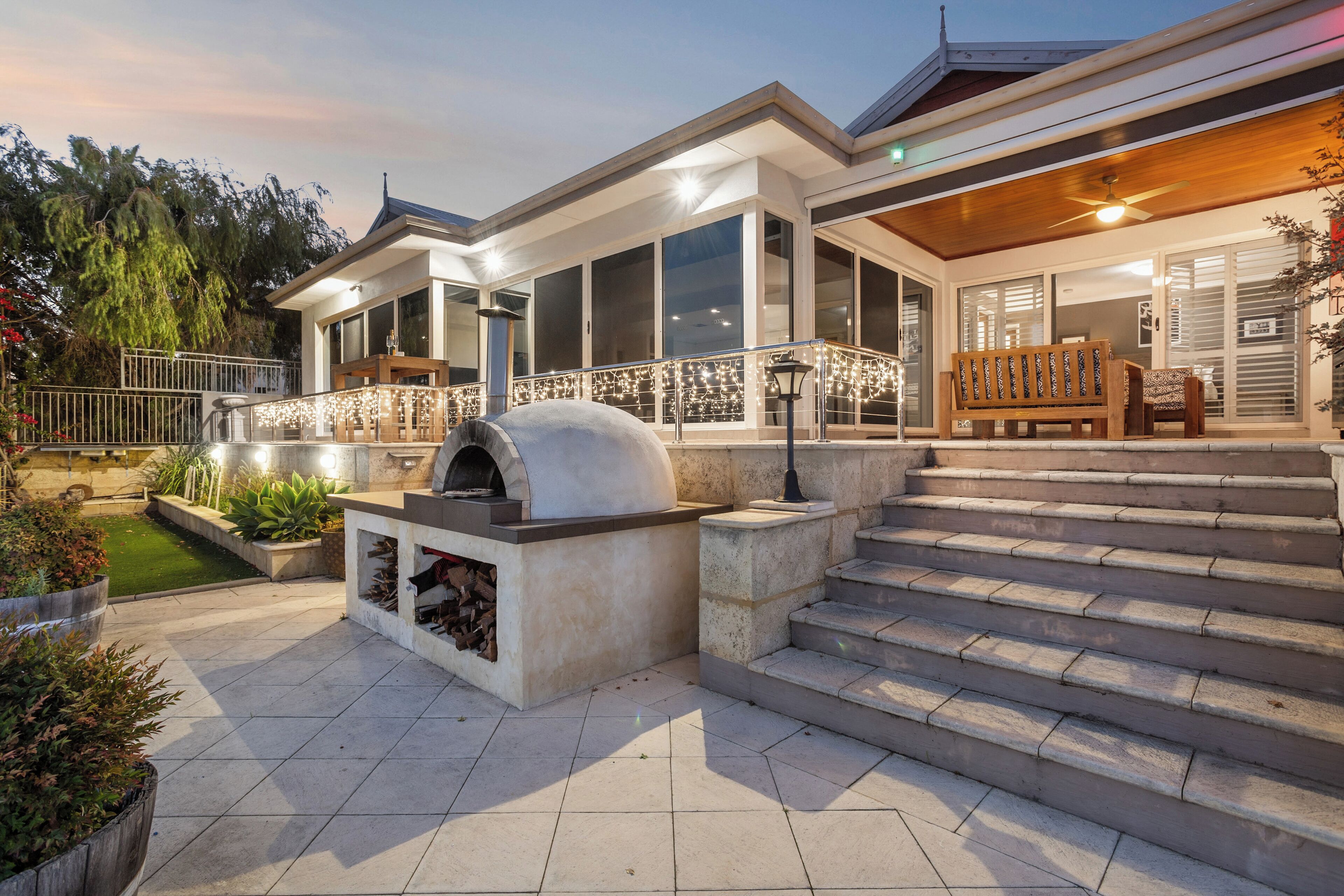Uma casa moderna com um alpendre, mobiliário de exterior e forno embutido.