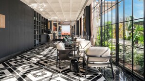 Un vestíbulo de hotel moderno con piso de diseño geométrico, zonas de estar y ventanas amplias que dan a zonas verdes.