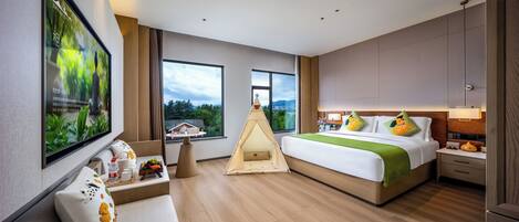 Ein modernes Hotelzimmer mit einem großen Bett, einer Sitzecke, einem Zelt und einem an der Wand montierten Fernseher.
