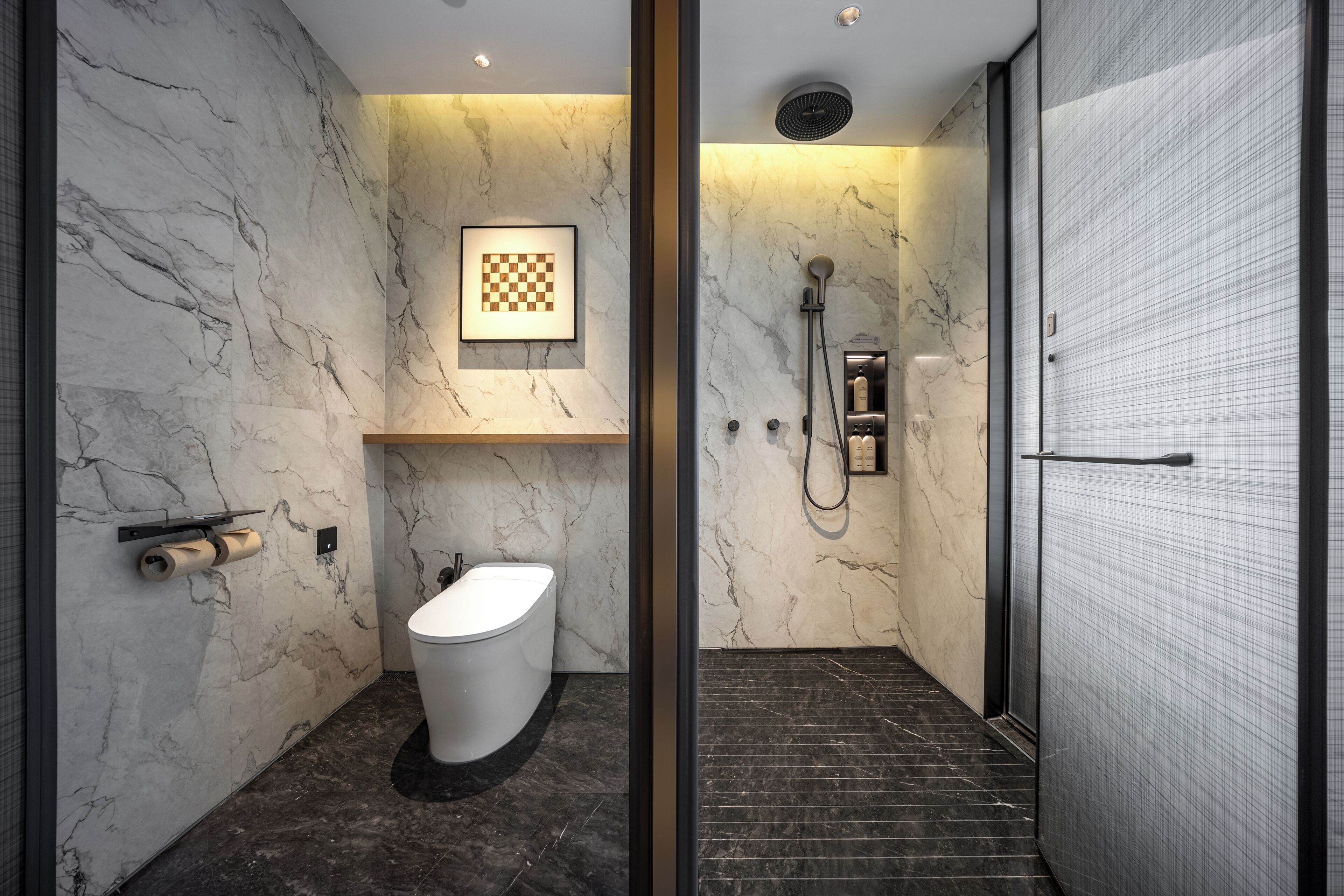 Un bagno moderno con una parete in marmo, un WC, una doccia e una scacchiera incorniciata.