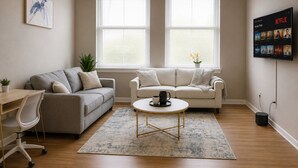 A living room with two sofas, a coffee table, a TV mounted on the wall, and a potted plant. - Playhouse SQ Downtown, R&R Hall, Clinic, CSU (Cleveland)