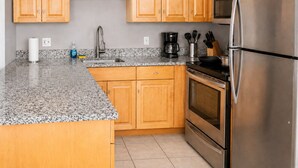 A kitchen with wooden cabinets, a stainless steel refrigerator, a coffee maker, and a sink. - Playhouse SQ Downtown, R&R Hall, Clinic, CSU (Cleveland)