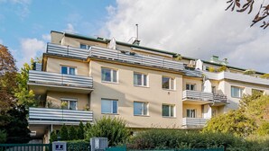 Un immeuble résidentiel à plusieurs étages, doté de balcons, d’une entrée sécurisée et d’un jardin bien entretenu.