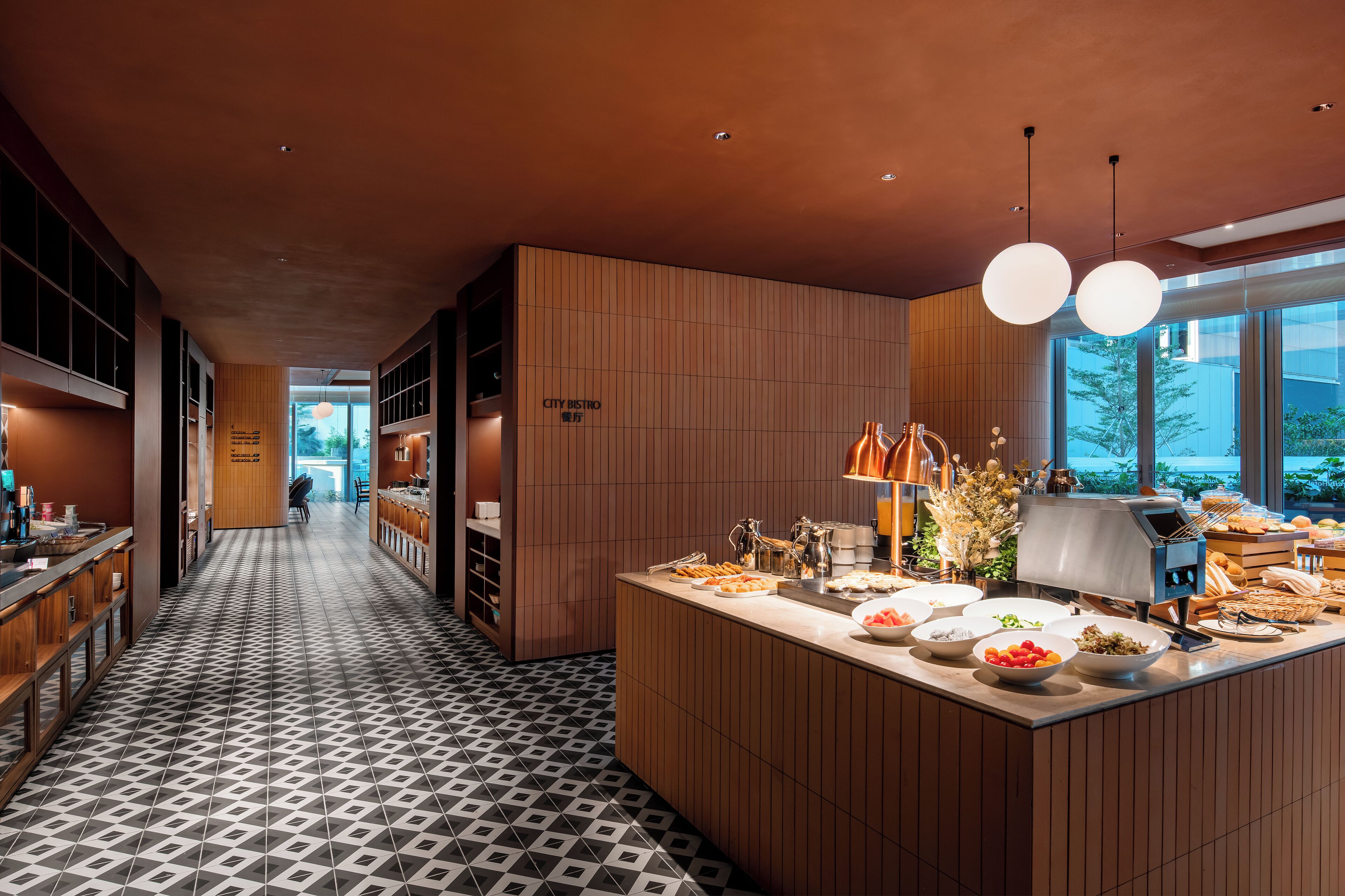 En modern bistro med en lång hall, träpanel och en frukostbuffé.