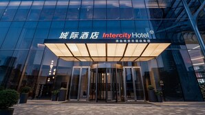 Entrada del Hotel Intercity, con fachada de vidrio moderna y puerta giratoria.