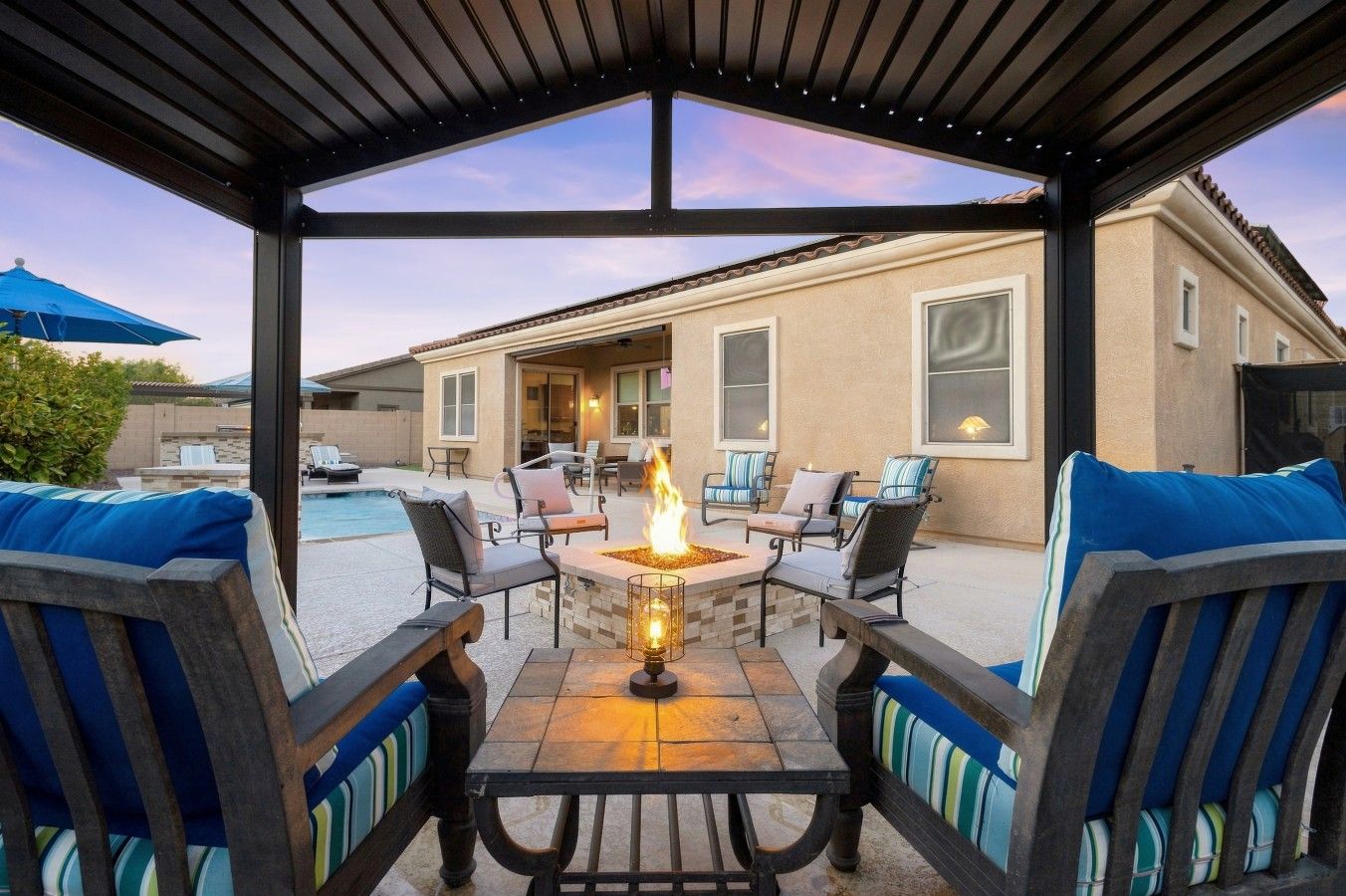 An outdoor patio with a fire pit, seating, and a view of a house.