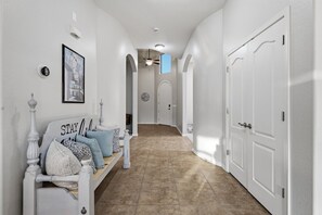 A hallway with a bench, a framed picture, and a door. - WoodHaven, Amazing Interior, Stunning Backyard, Combined Pool & Spa 11 x 20 Feet (Goodyear)