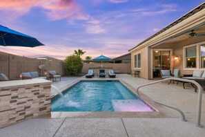 Un jardin avec une piscine, des chaises longues et un patio couvert.