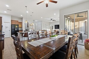 A spacious dining area with a wooden table, chairs, and a ceiling fan. - WoodHaven, Amazing Interior, Stunning Backyard, Combined Pool & Spa 11 x 20 Feet (Goodyear)