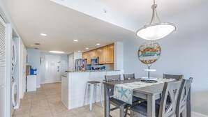 A spacious kitchen with wooden cabinets, a central island, and a dining area with a table and chairs. - Vitamin SEA Condo 7️⃣2️⃣7️⃣2️⃣5️⃣1️⃣8️⃣6️⃣5️⃣9️⃣ (Treasure Island)