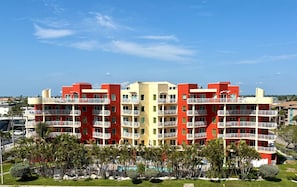 Um hotel com vários andares, varandas, piscina e vista para o mar.