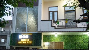 Um hotel com uma parede verde e uma varanda com plantas em vasos.