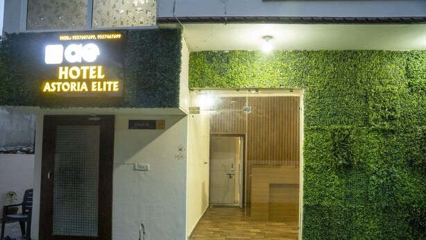 Entrada de hotel com parede verde e placa de check-in.