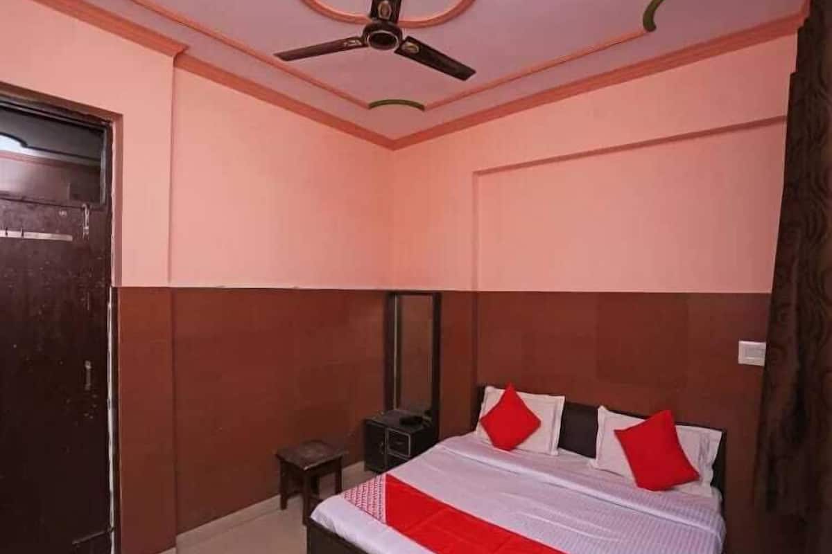 Un dormitorio con cama, ventilador de techo, una mesita y un armario.