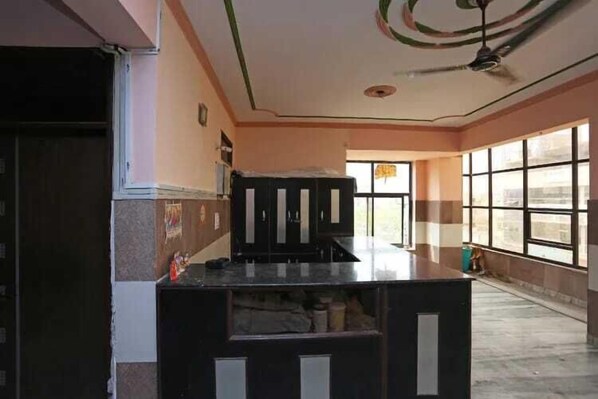 A room with a large window, a ceiling fan, and a counter with cabinets. - Hotel Bombay Central Agra (Agra)