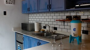 Une cuisine avec des meubles de rangement bleus, un four à micro-ondes, un évier et un grille-pain.