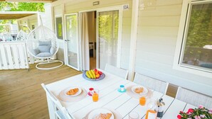 A covered outdoor dining area with a table set for breakfast, including croissants and fruit.