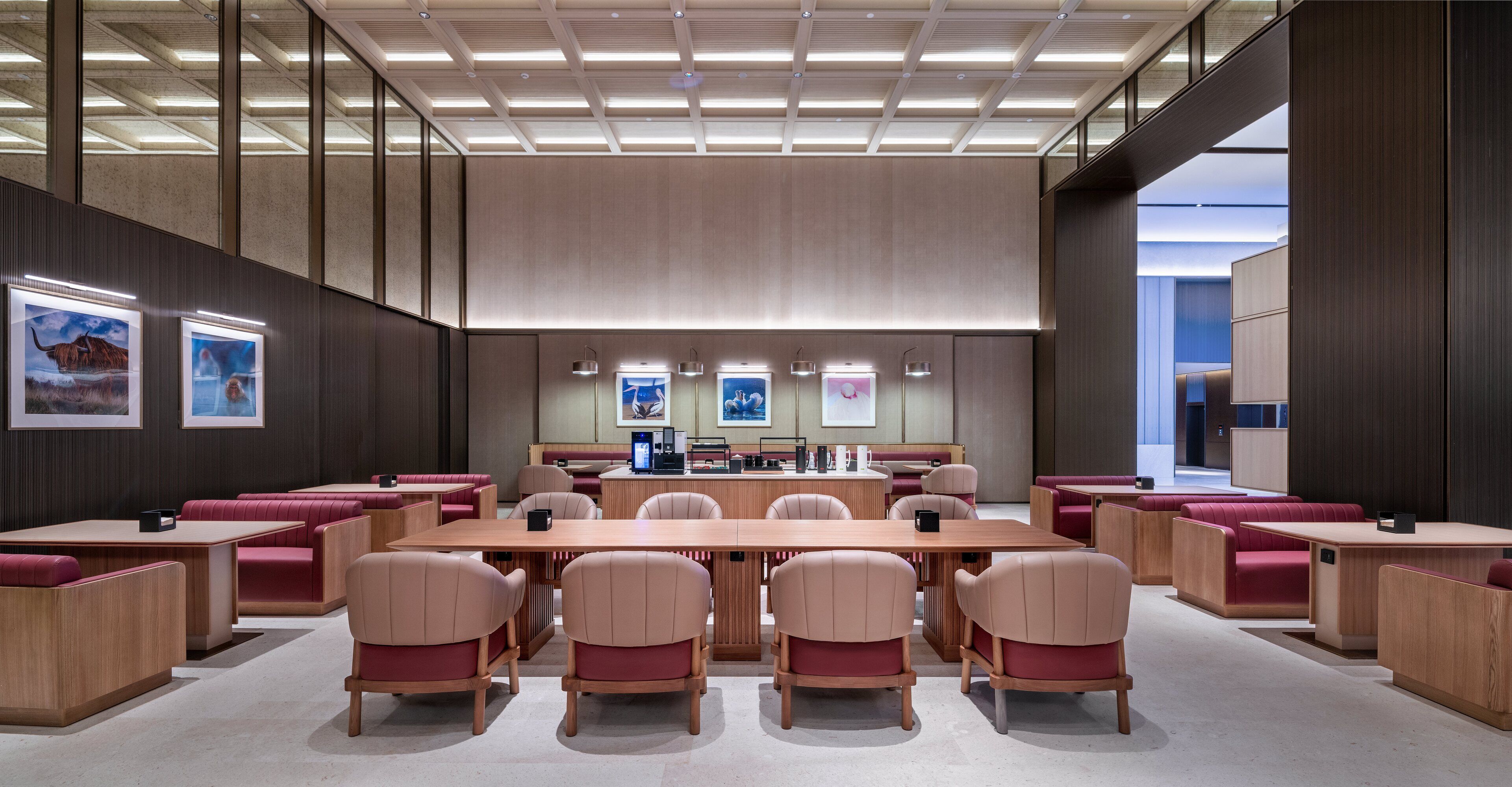 A spacious conference room with a long table and multiple chairs, a coffee station, and framed artwork on the walls.
