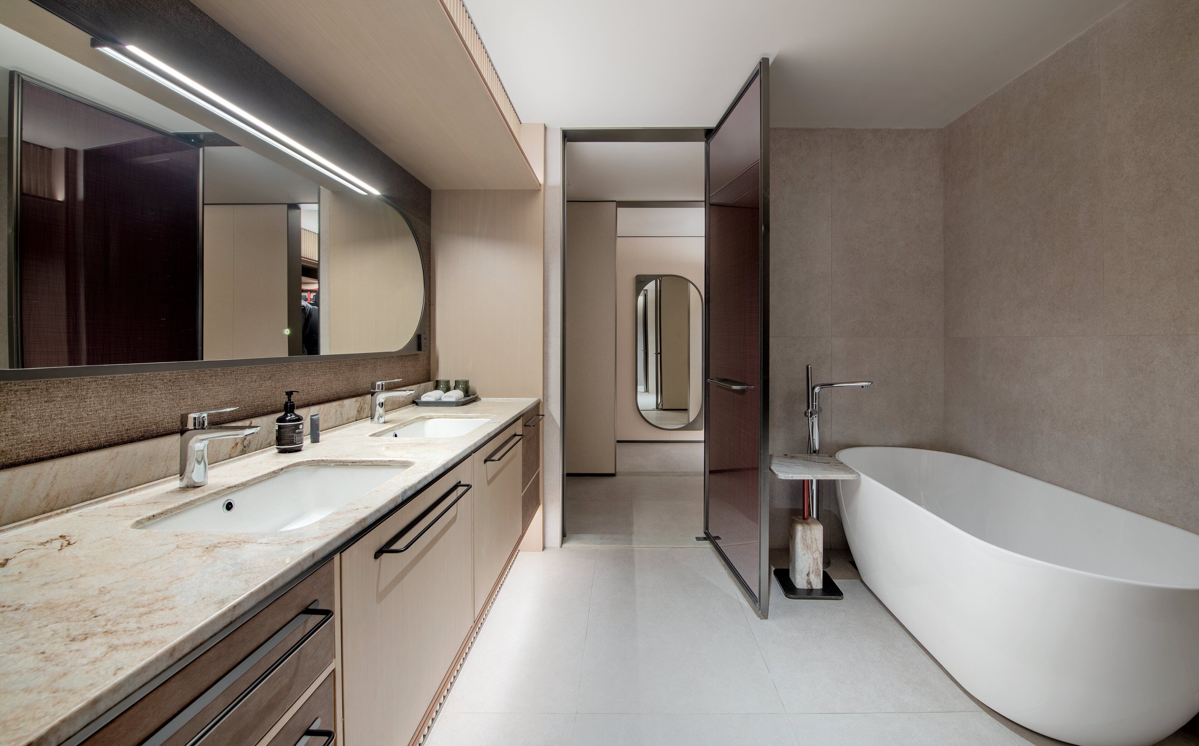 Un baño moderno con una bañera independiente, un tocador doble y un espejo grande.