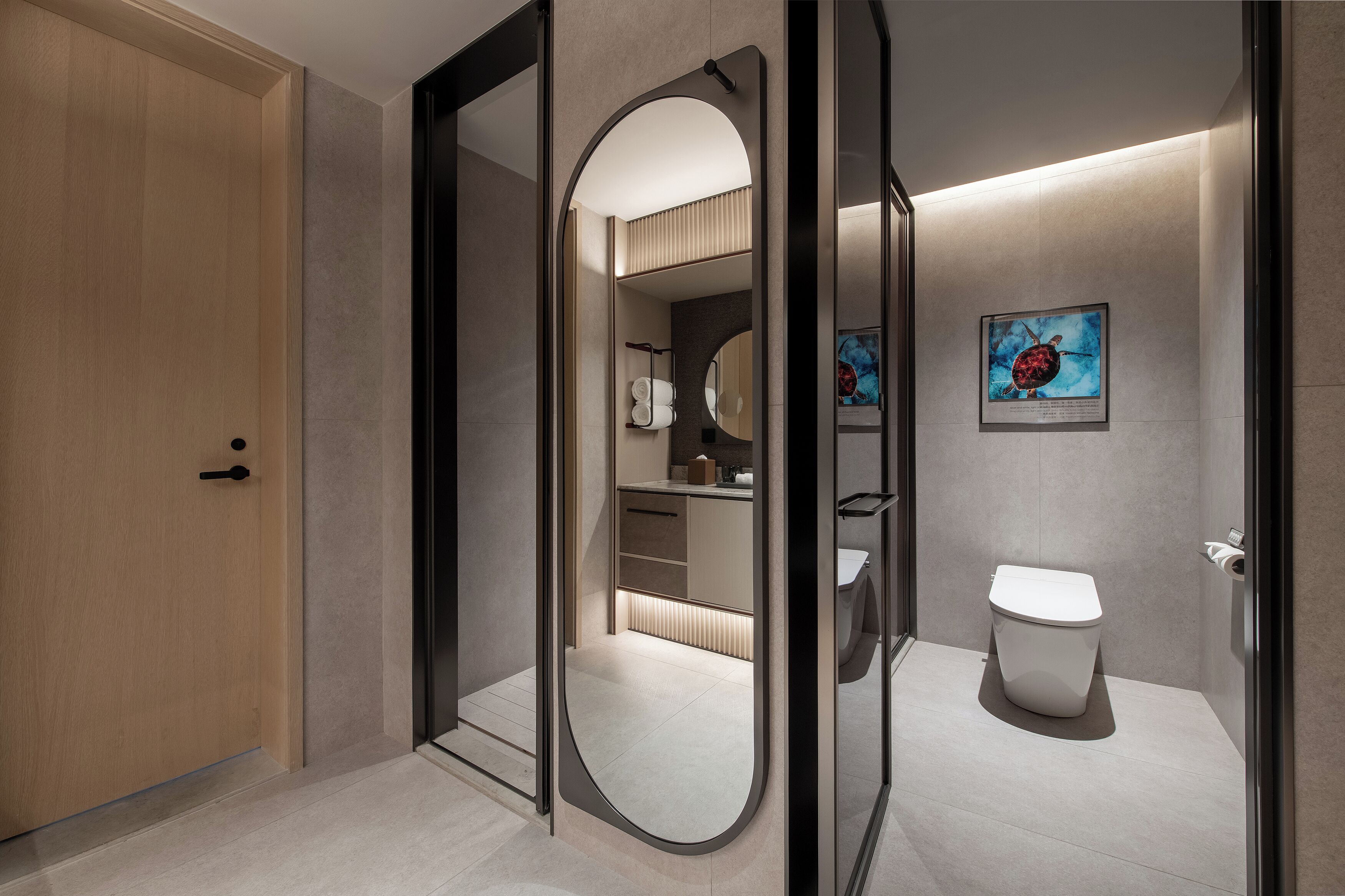 A modern bathroom with a toilet, a sink, and a mirror. There is a door leading to another room.