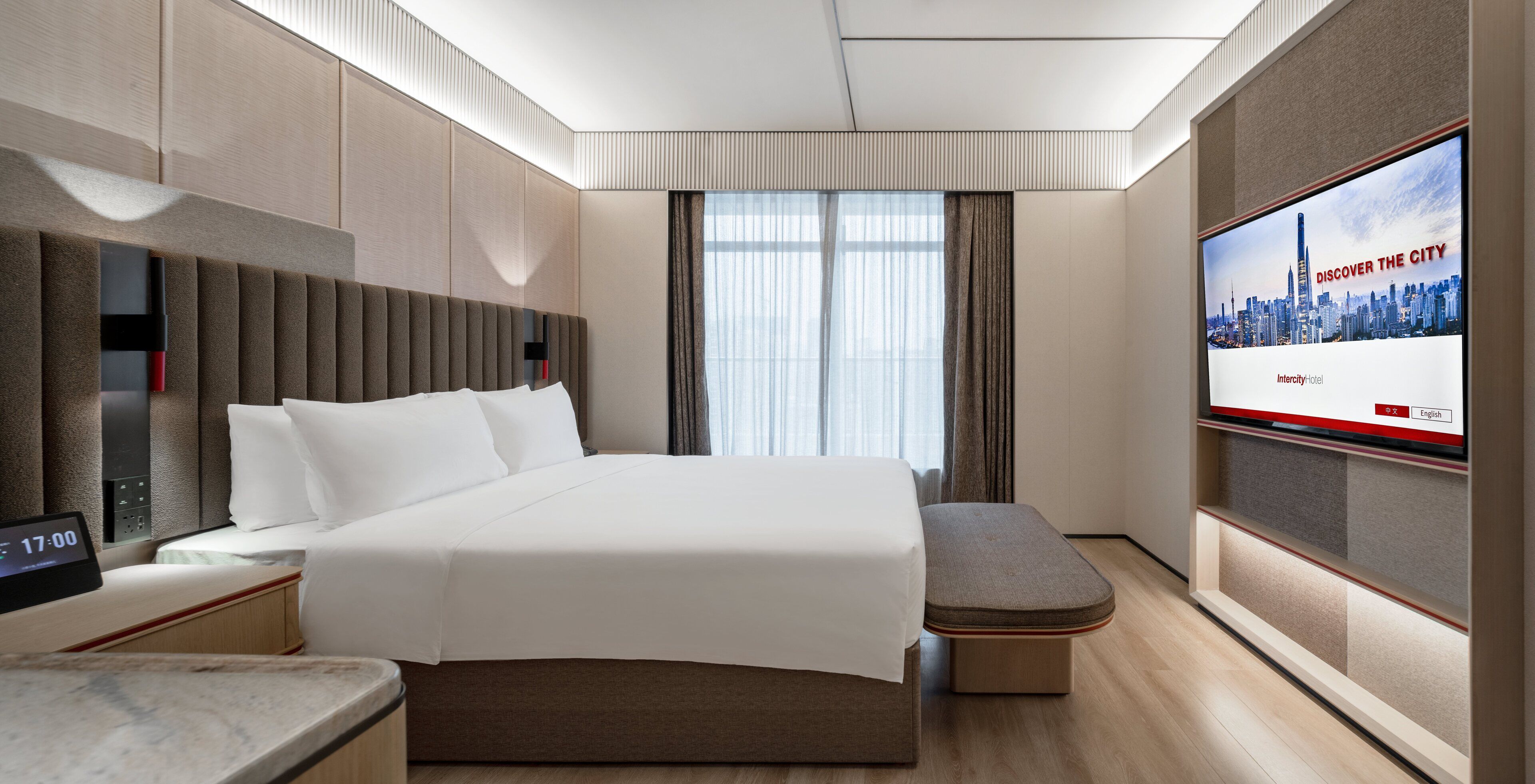 A modern hotel room with a bed, a TV, a bedside table, and a window with curtains.