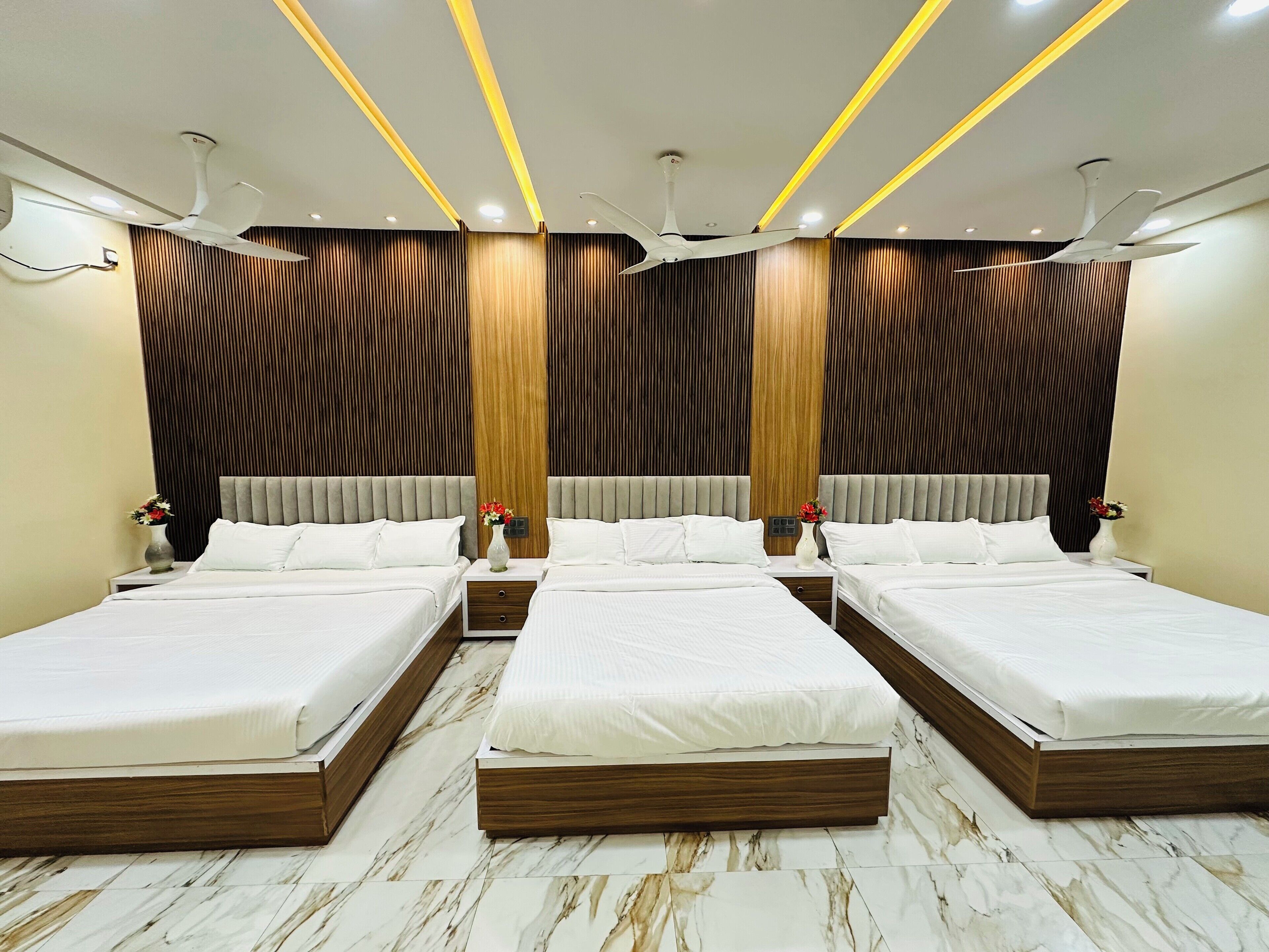 A hotel room with a modern design, featuring a large bed with a wooden frame, two bedside tables, and a wall-mounted ceiling fan.