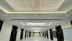 A spacious hallway with a polished marble floor, elegant chandeliers, and modern lighting fixtures. - Anand Resort (Durg)