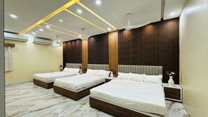 A modern hotel room with three beds, marble flooring, wooden panel walls, and recessed lighting. - Anand Resort (Durg)