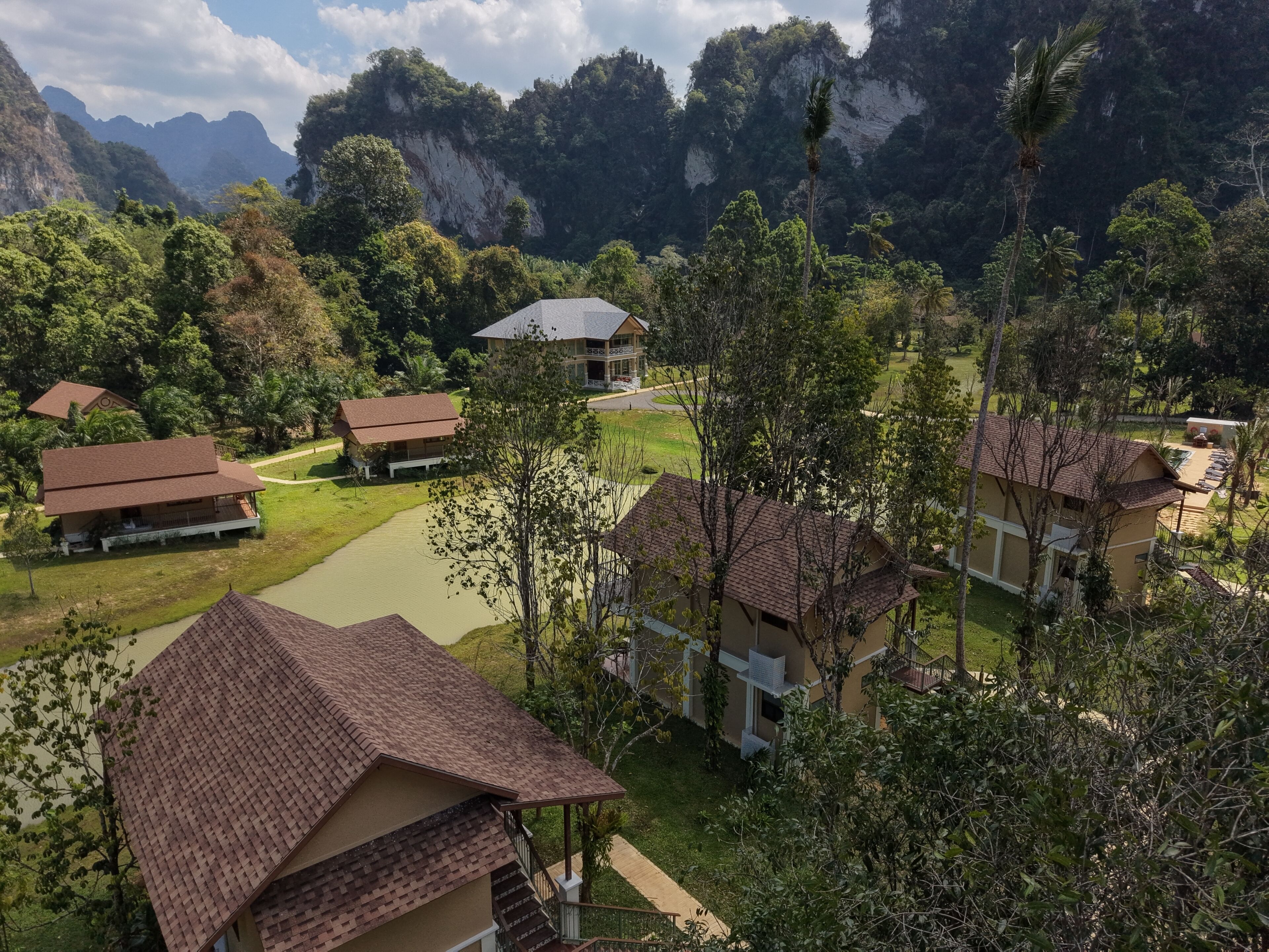 A resort with multiple buildings, a swimming pool, and a mountainous backdrop.