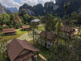 Un complejo turístico con varias edificaciones, una piscina y montañas al fondo.