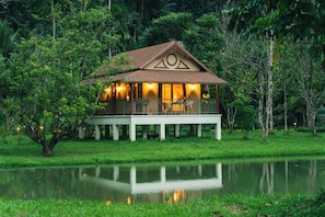A bungalow with a balcony, surrounded by lush greenery and a body of water. - Lost Horizon Resort - Khao Sok (Phanom)