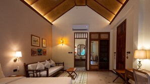 Hotelkamer met een bed, een bank, een bureau en een badkamer die door een open deur zichtbaar is.