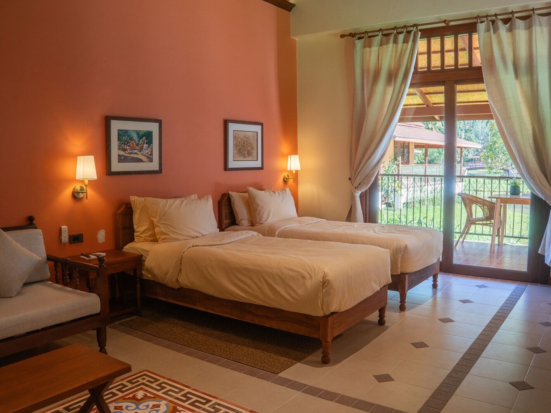 A hotel room with two beds, a sofa, a small table, and a balcony with a chair.